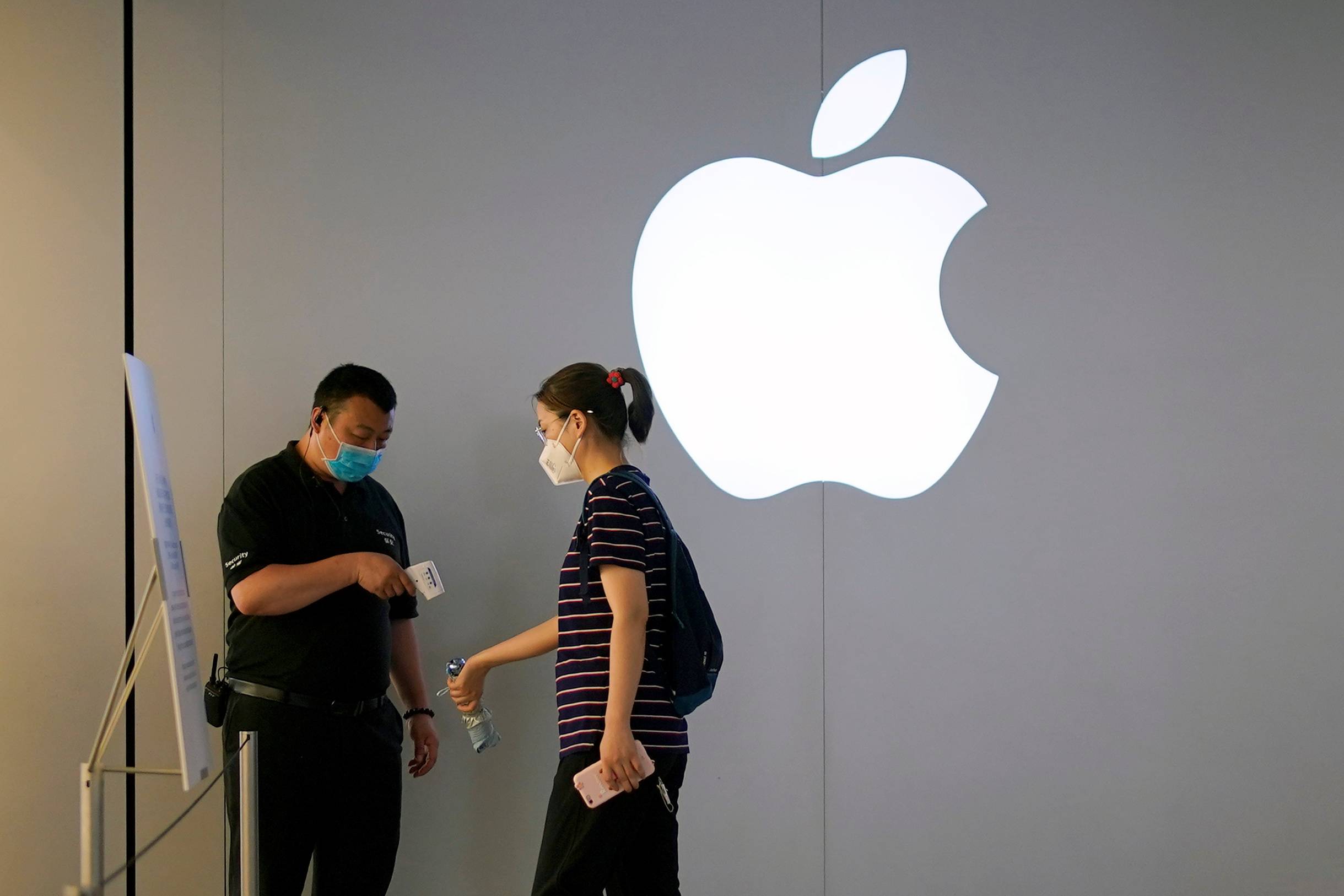 A woman wearing a protective face mask waits to measure her temperature in an Apple Store following the coronavirus disease (COVID-19) outbreak, in Shanghai